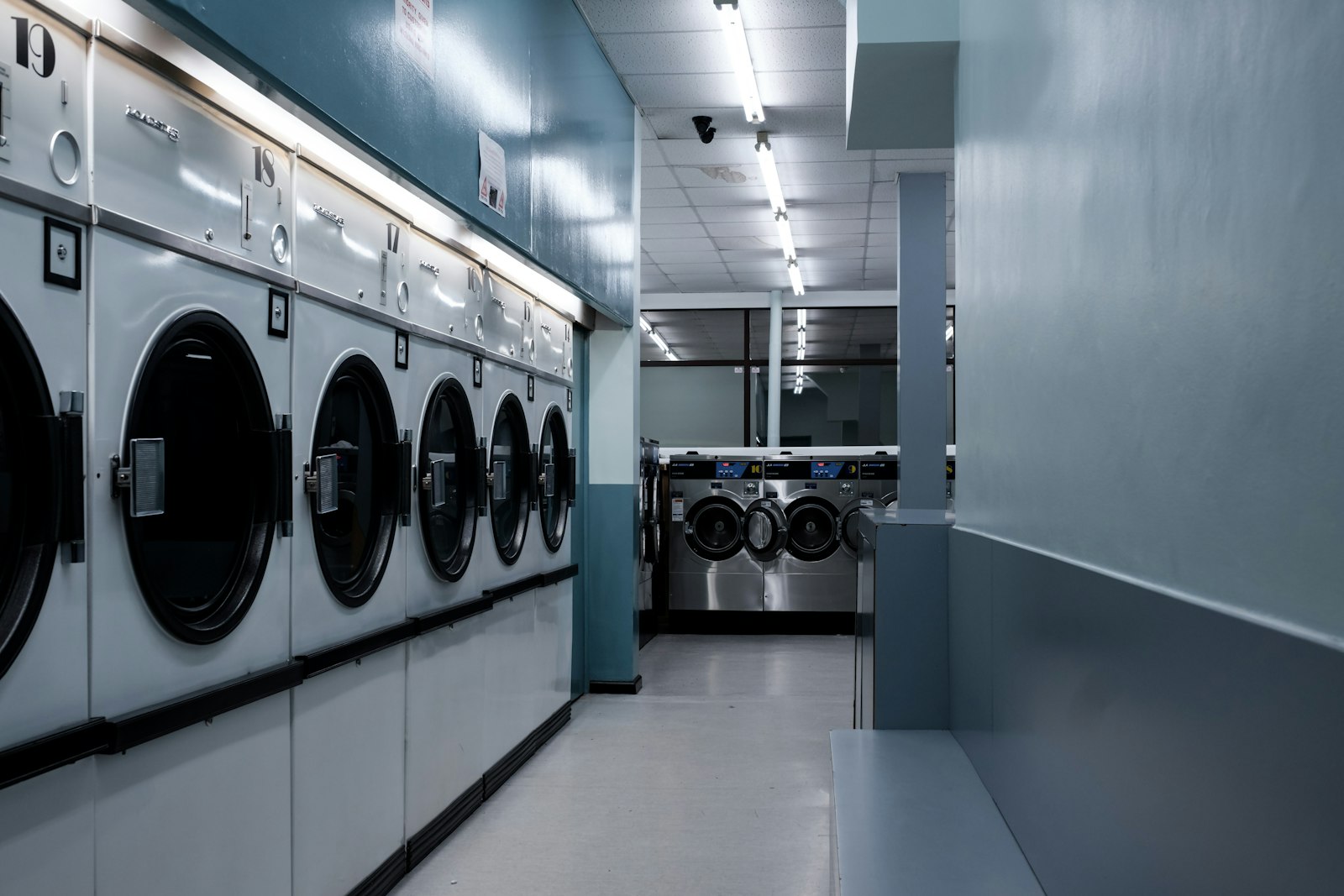 Industrial laundry facility with rows of washing machines (stock photo, placeholder)